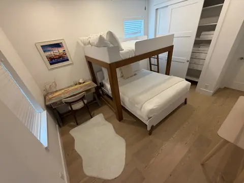 Guest room with made bunk beds and folded towels in an open closet