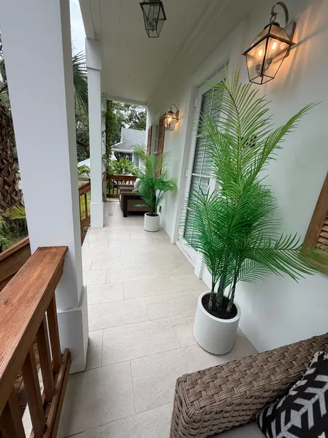 Tiled porch with palm plants, lanterns and wicker seating