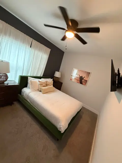 Guest bedroom with a green upholstered bed and neatly arranged white pillows