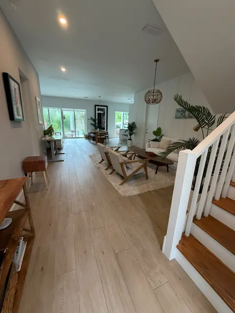 Open living and dining room with pale tile floors and tropical plants
