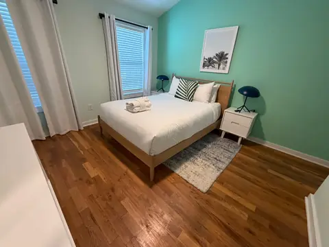 Mint-green bedroom with white bedding and folded guest towels