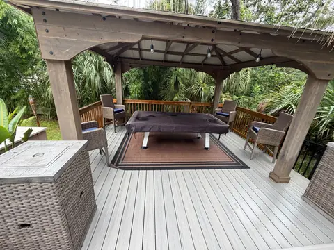 Covered wooden deck with arranged wicker chairs and a covered game table
