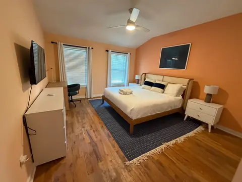 Peach-colored bedroom with white linens, a cane headboard and folded towels
